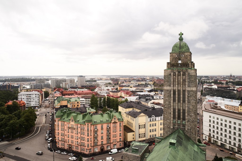 Näkymä Helsingin Kallion kaupunginosaan, etualalla Kallion kirkko ja sen korkea torni, taustalla kaupungin rakennuksia ja merimaisemaa.